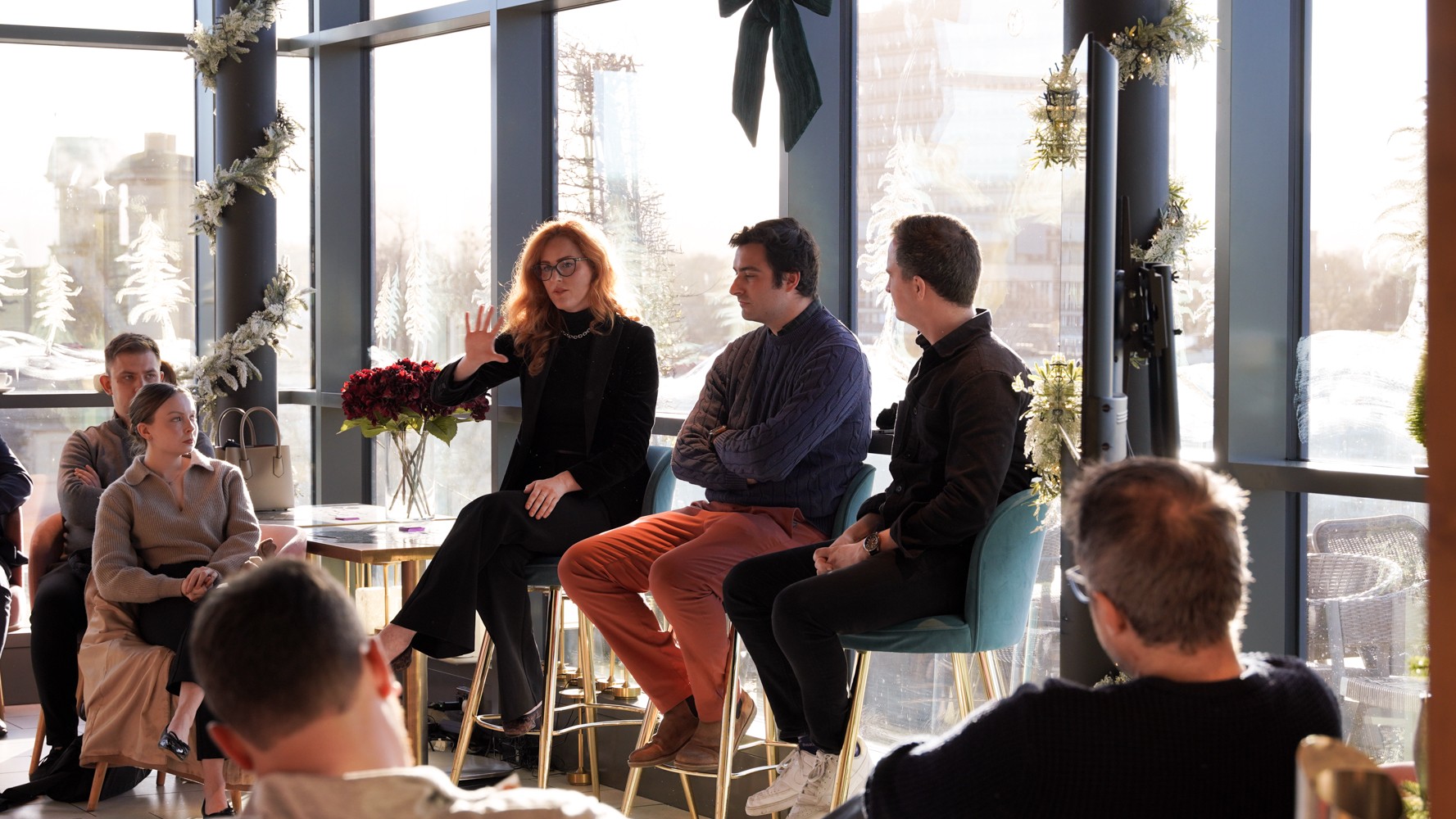 Two women sitting at a modern table talking with a city view behind them.