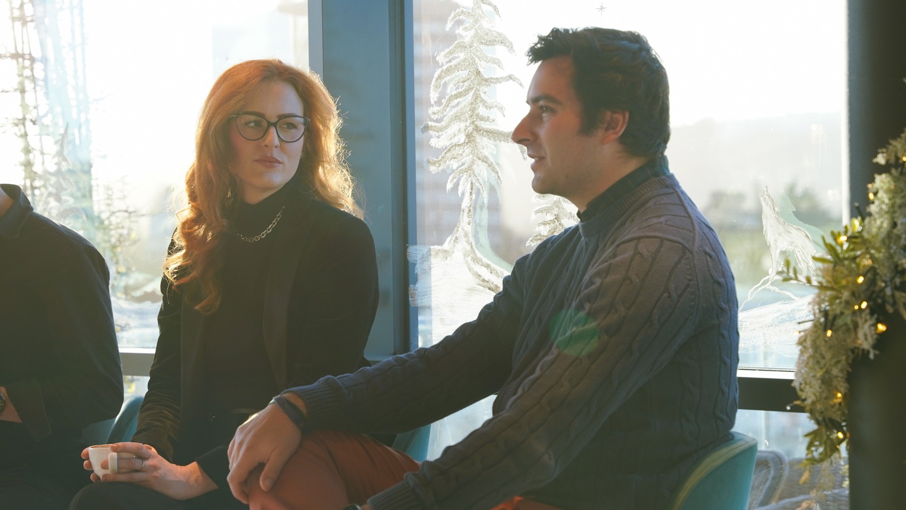 Photo of two women and a man talking in the corner of a room with modern furniture.